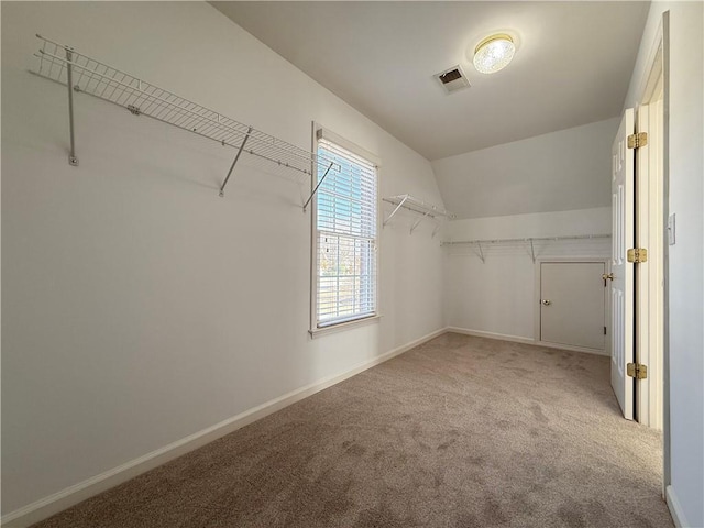 spacious closet with vaulted ceiling and light colored carpet