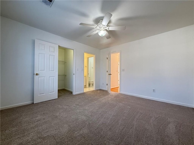 unfurnished bedroom with connected bathroom, carpet floors, a spacious closet, ceiling fan, and a closet