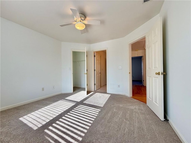 unfurnished bedroom with a walk in closet, light colored carpet, ceiling fan, and a closet