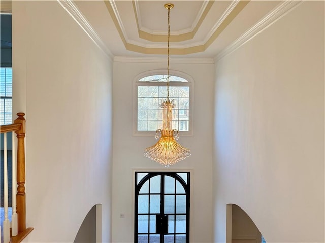 interior details featuring french doors, ornamental molding, a notable chandelier, and a tray ceiling