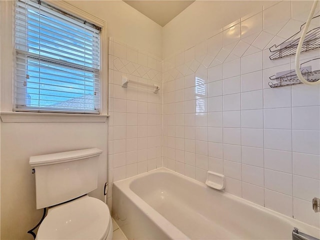 bathroom featuring tiled shower / bath combo and toilet