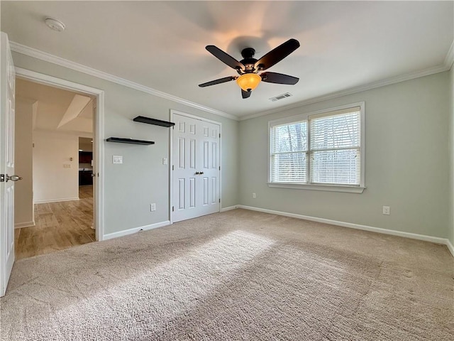 unfurnished bedroom featuring ceiling fan, light colored carpet, ornamental molding, and a closet