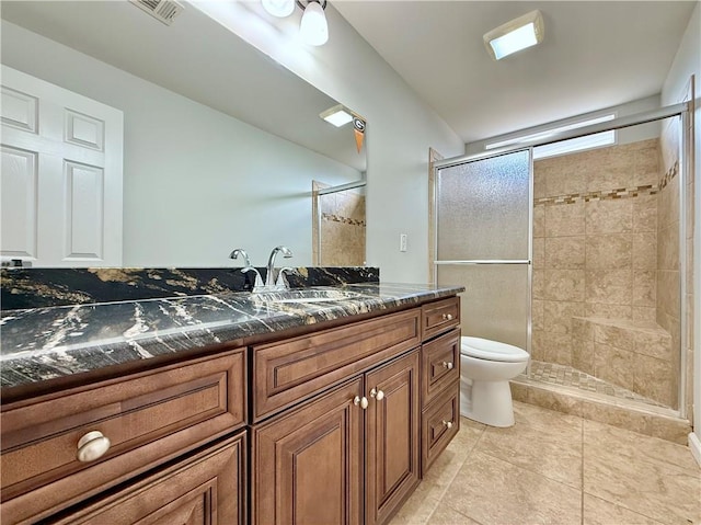 bathroom featuring a shower with door, vanity, tile patterned floors, and toilet