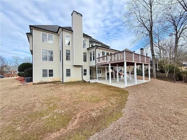 back of property featuring a wooden deck, a yard, and a patio area