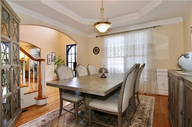 dining room with crown molding, a tray ceiling, and wood-type flooring