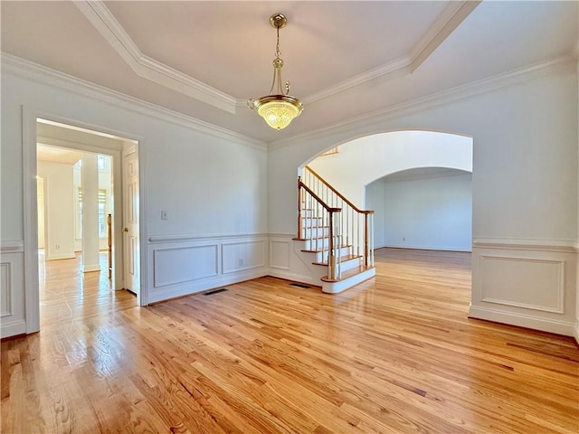 spare room featuring ornamental molding, a raised ceiling, and light hardwood / wood-style floors