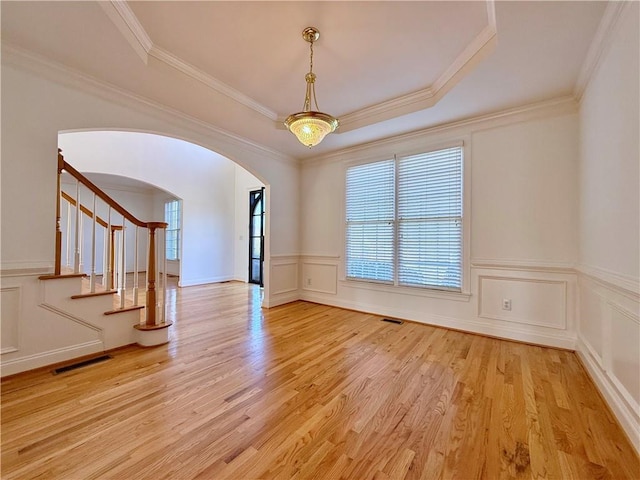 spare room featuring ornamental molding, light hardwood / wood-style floors, and a tray ceiling