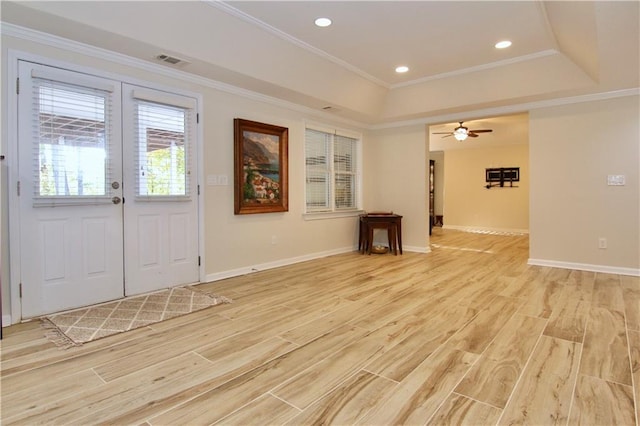 interior space with crown molding, light hardwood / wood-style flooring, a raised ceiling, and french doors