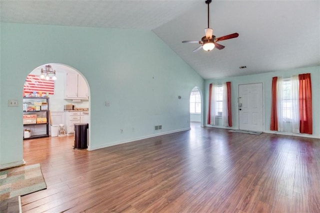 1015 Carriage Way, Loganville, GA 30052 - unfurnished living room with arched walkways, a ceiling fan, wood finished floors, high vaulted ceiling, and a chandelier