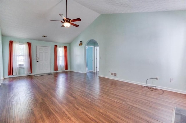 1015 Carriage Way, Loganville, GA 30052 - unfurnished living room with a ceiling fan, arched walkways, wood finished floors, baseboards, and vaulted ceiling