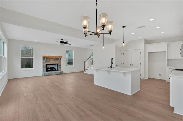 kitchen featuring light countertops, visible vents, a sink, a stone fireplace, and light wood-type flooring