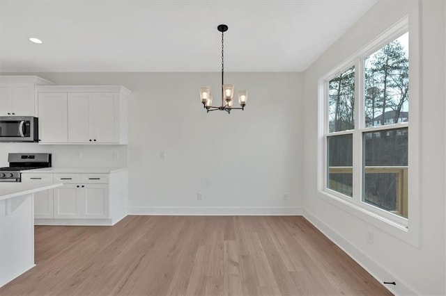 kitchen featuring stainless steel appliances, light wood finished floors, light countertops, and baseboards