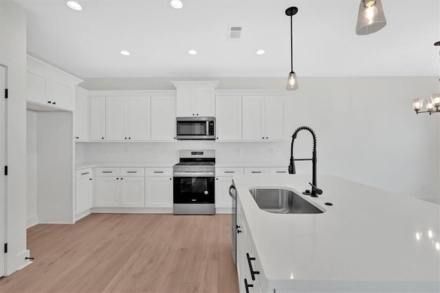 kitchen featuring a sink, white cabinetry, visible vents, light wood-style floors, and appliances with stainless steel finishes