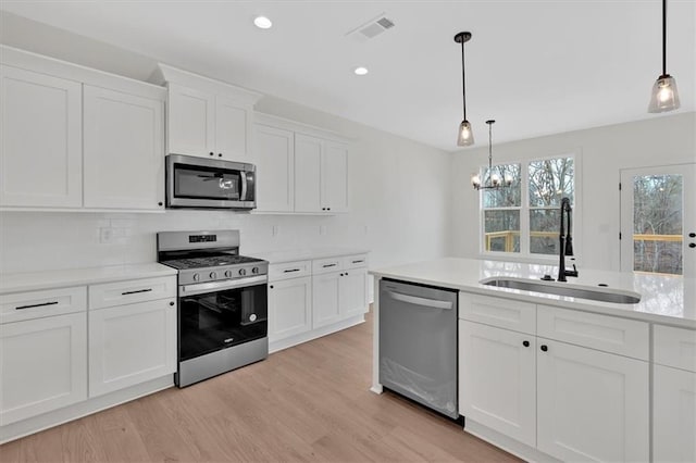 kitchen featuring visible vents, appliances with stainless steel finishes, light countertops, light wood-type flooring, and a sink