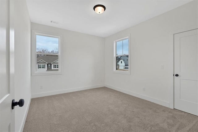 empty room with carpet floors, baseboards, and visible vents