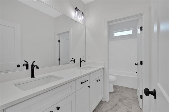 bathroom featuring toilet, marble finish floor, double vanity, and a sink