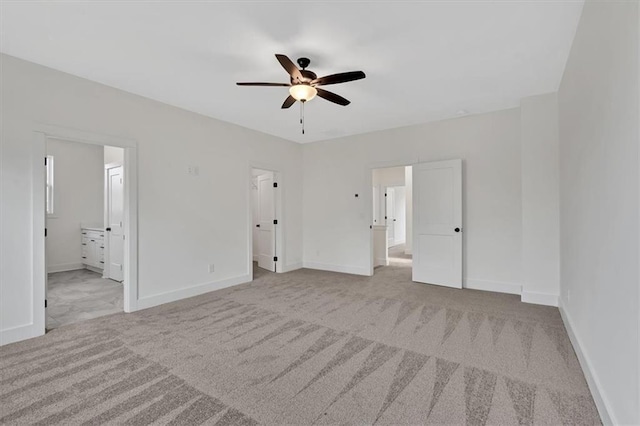 unfurnished bedroom with carpet floors, ceiling fan, ensuite bath, and baseboards