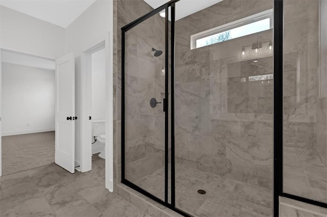 bathroom with marble finish floor, a shower stall, and toilet