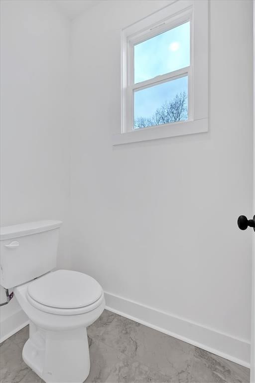 bathroom featuring marble finish floor, toilet, and baseboards