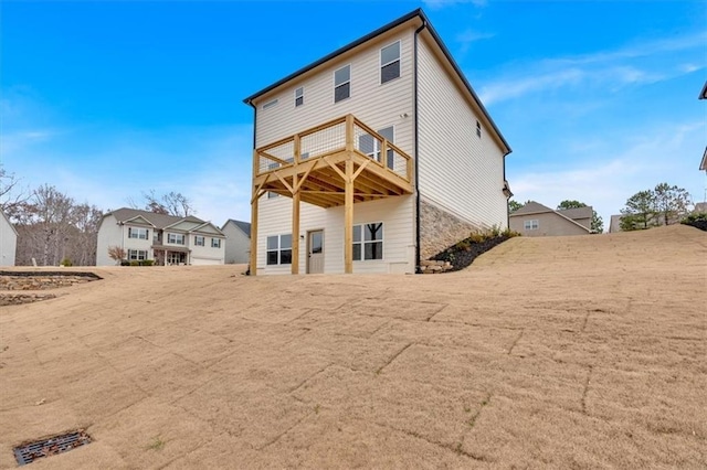 back of house featuring stone siding and a wooden deck