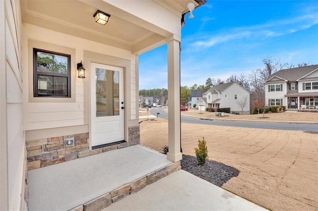 view of exterior entry featuring covered porch and a residential view