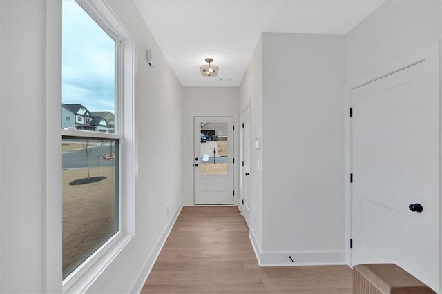 hall featuring light wood-style flooring and baseboards