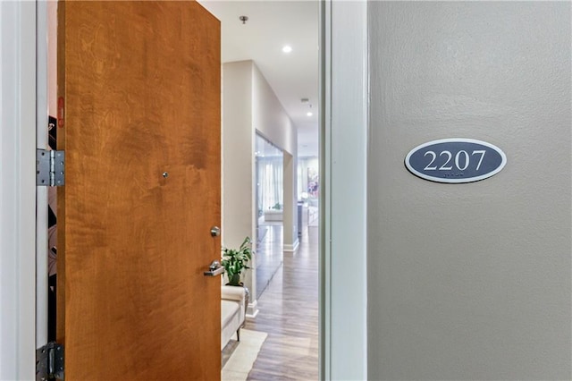 hall with recessed lighting, baseboards, wood finished floors, and a textured wall