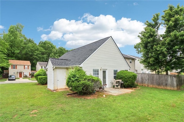 rear view of house featuring a lawn, fence, and a shingled roof