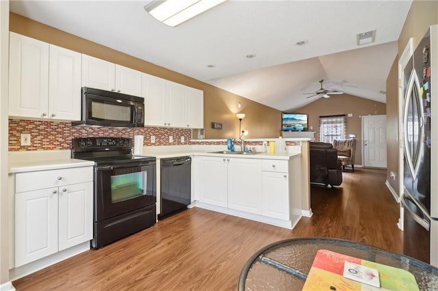 kitchen with wood finished floors, a sink, black appliances, a peninsula, and open floor plan