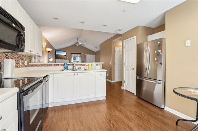 kitchen featuring a ceiling fan, a sink, black appliances, a peninsula, and light wood-style floors