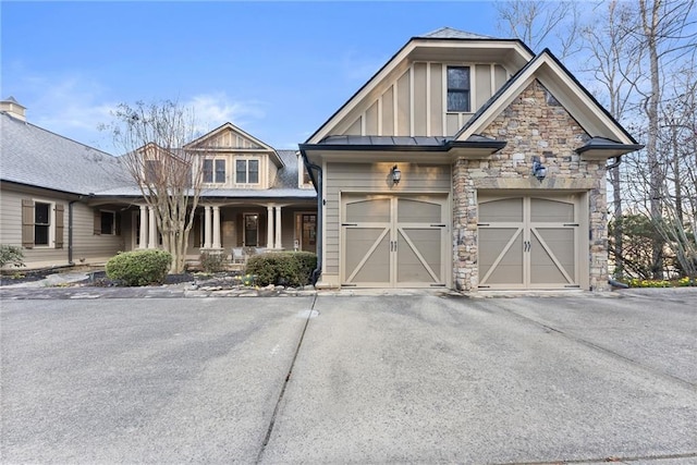 craftsman inspired home featuring a porch, stone siding, board and batten siding, and driveway