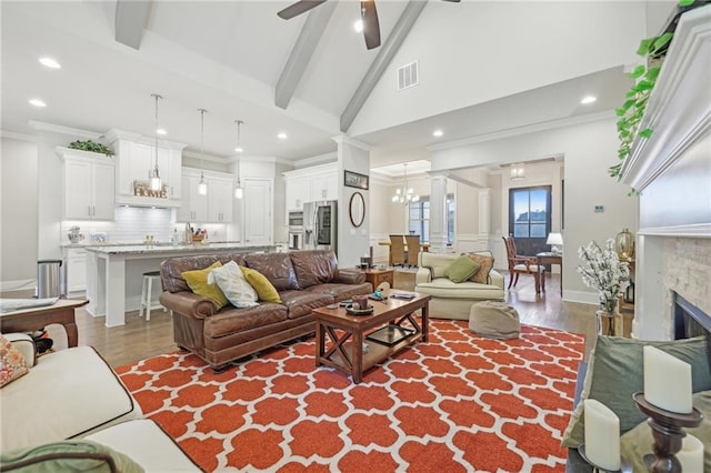 living room featuring beamed ceiling, wood-type flooring, high vaulted ceiling, ceiling fan with notable chandelier, and crown molding