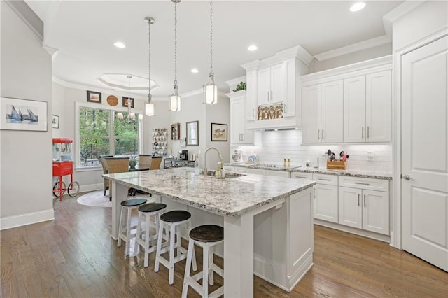 kitchen featuring a kitchen island with sink, dark hardwood / wood-style flooring, sink, and white cabinetry