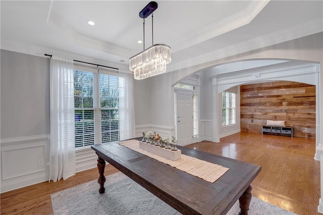 dining area featuring plenty of natural light, a raised ceiling, and light hardwood / wood-style floors