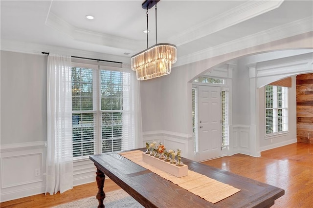 dining area featuring crown molding, plenty of natural light, light wood-type flooring, and a tray ceiling