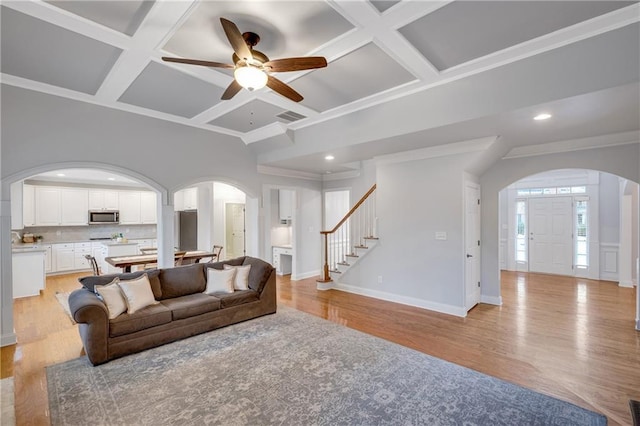 living room with coffered ceiling, beam ceiling, ornamental molding, and light hardwood / wood-style floors