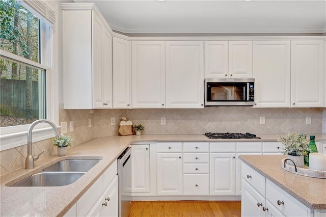 kitchen with stainless steel appliances, sink, white cabinets, and decorative backsplash