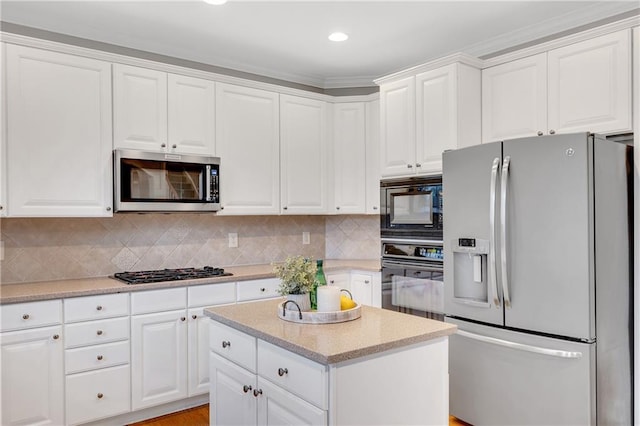 kitchen with a kitchen island, appliances with stainless steel finishes, white cabinets, and backsplash