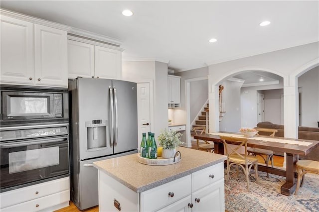 kitchen with black appliances, a center island, and white cabinets