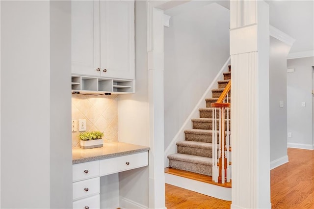 interior space featuring hardwood / wood-style floors, built in desk, and ornamental molding