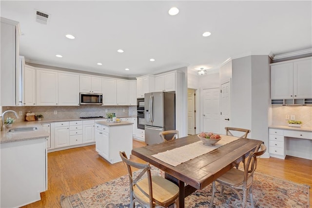 kitchen featuring a kitchen island, white cabinetry, sink, black appliances, and light wood-type flooring