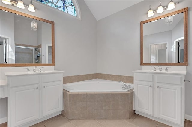 bathroom featuring tile patterned flooring, vaulted ceiling, shower with separate bathtub, and vanity