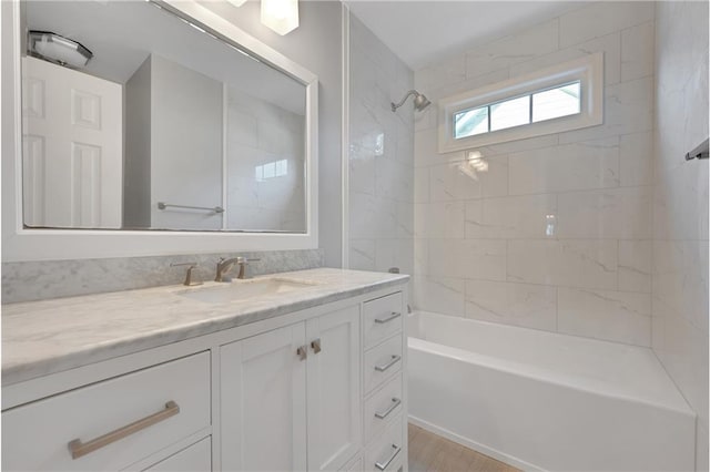 bathroom featuring hardwood / wood-style flooring, tiled shower / bath, and vanity