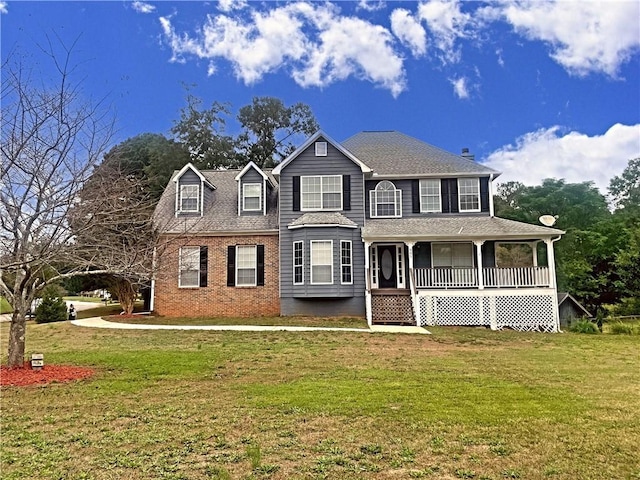 view of front facade featuring covered porch, roof with shingles, a front lawn, and brick siding