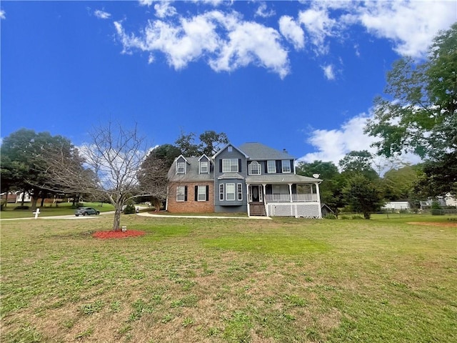 view of front of property featuring covered porch, a front lawn, and brick siding