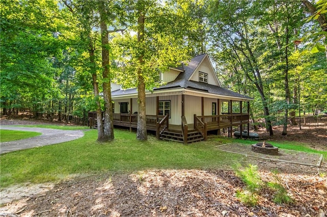 back of property with a lawn, an outdoor fire pit, and a wooden deck