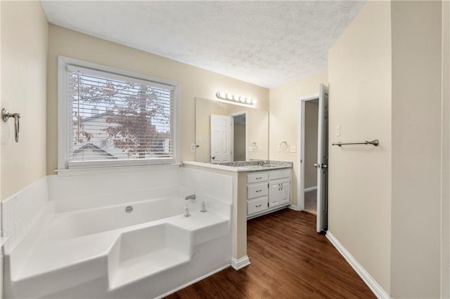 bathroom featuring vanity, a bath, a textured ceiling, and wood-type flooring