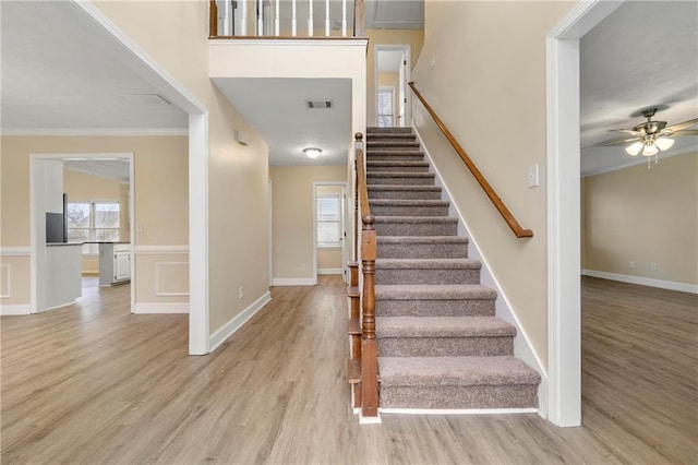 stairs with hardwood / wood-style flooring, plenty of natural light, ceiling fan, and crown molding