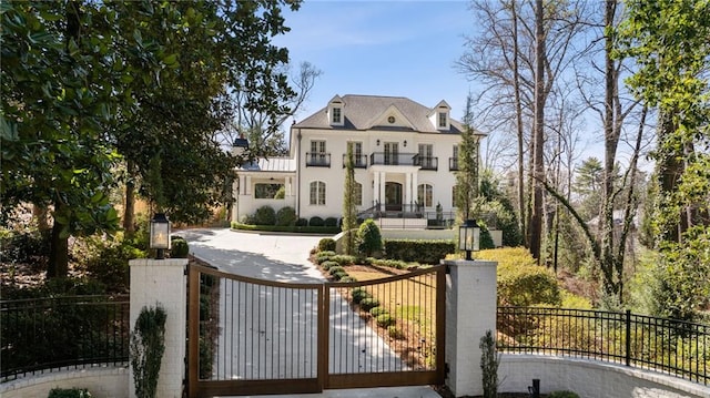 view of front of home with a fenced front yard, a balcony, and a gate