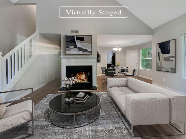 living room featuring lofted ceiling, an inviting chandelier, and hardwood / wood-style flooring